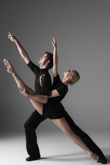 two young modern ballet dancers on gray studio background 