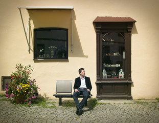 Young Businessman is Sitting on Bench in Historical Town