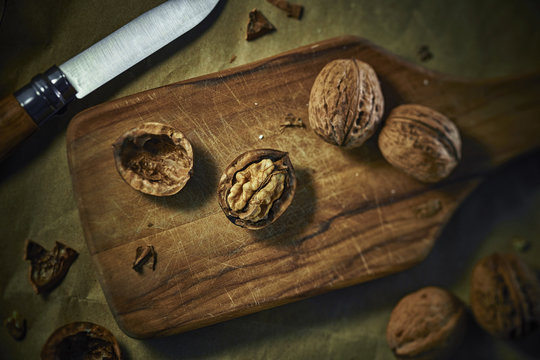 Cracked and whole walnuts on wooden board