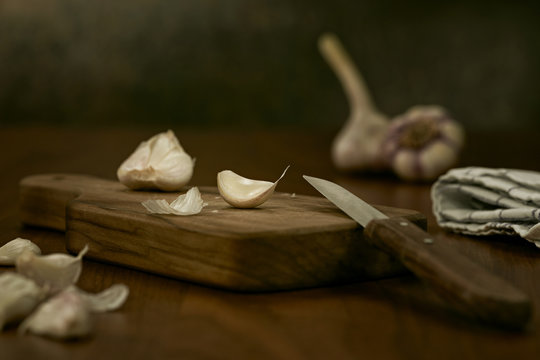 Garlic cloves and knife on wooden board