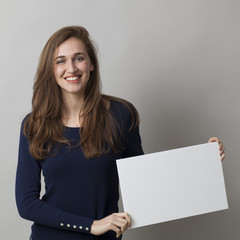 Naklejka premium thrilled young girl holding a white communication board with positive news on