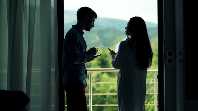 Couple with tablet computer drinking tea while standing on terrace
