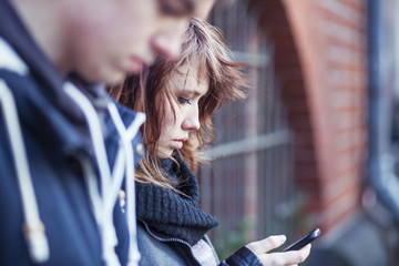 Teenage girl with smartphone, boy blurred in the foreground
