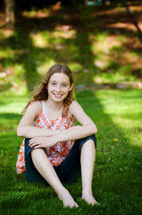 pretty teen girl sitting outdoors on a sunny summer day