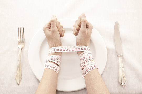 Woman in front of empty plate bound with tape measure