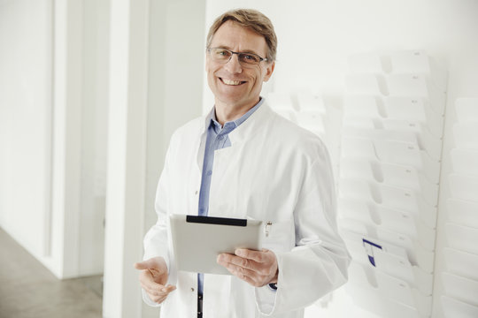 Smiling Mature Man In Lab Coat Holding Digital Tablet