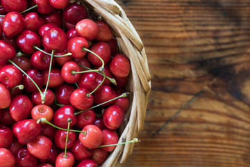 Ripe organic homegrown cherries in a basket, on wooden background
