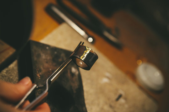 Goldsmith working on wedding rings, holding workpiece with forceps