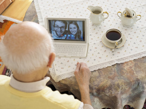 Grandfather videoconferencing with grandchildren via digital tablet