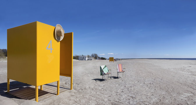Yellow changing cubicle and two folding chairs on empty sandy beach