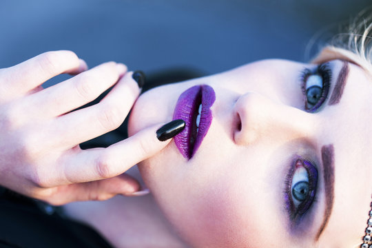 Portrait of rouged blond woman with finger on mouth