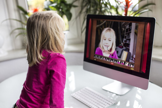 Little girl watching herself on flat screen monitor