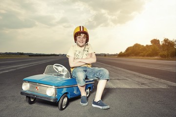 Smiling boy with pedal car on race track