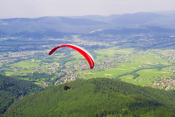 Obrazy na Plexi  Paralotnia nad wioską w górach