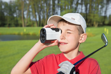 boy golfer watching into rangefinder - obrazy, fototapety, plakaty