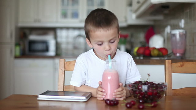 Happy school boy drinking  healthy smoothie as a snack at home