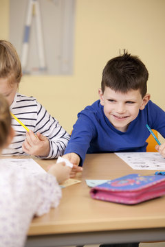 Pupils handing over slip of paper in classroom