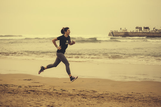 Spain, Gijon, Woman jogging at the beach