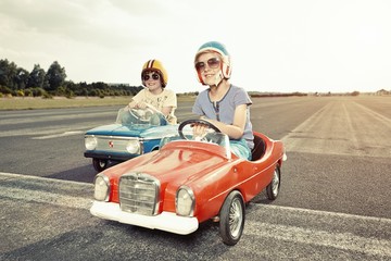 Two boys in pedal cars crossing finishing line on race track
