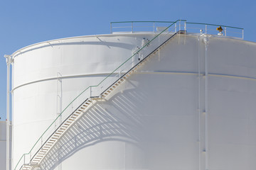 white tanks in tank farm with iron staircase