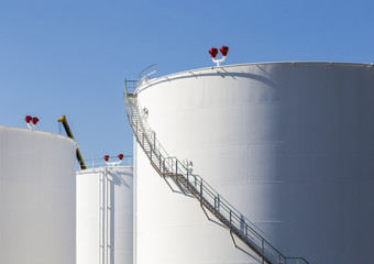 white tanks in tank farm with iron staircase