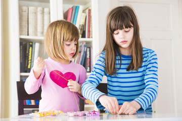 Two girls stringing pearls