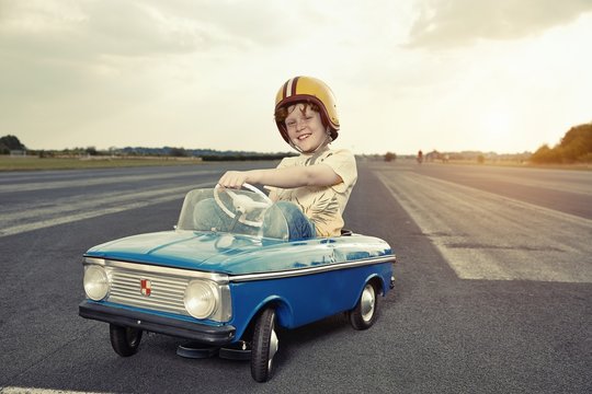 Smiling boy in pedal car on race track