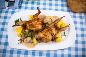 Two fried quail with gnocchi, gravy and rosemary