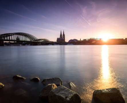 K&ouml;lner Dom als Siluette mit der Deutzer Br&uuml;cke und der Untergehenden Sonne mit Spiegelung im Rhein