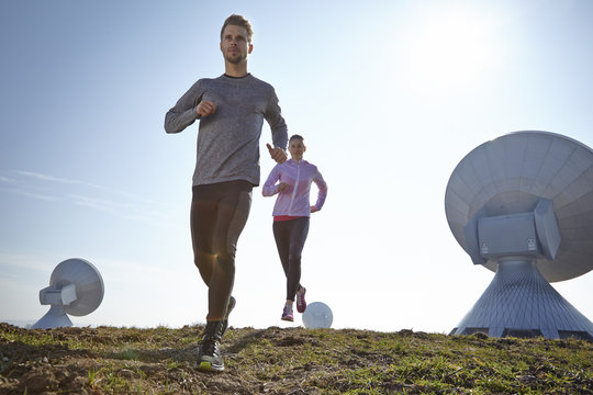 Germany, Raisting, young couple jogging at ground station