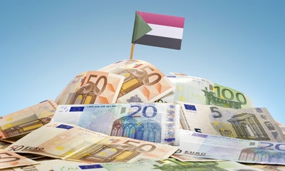 Flag of Sudan sticking in a pile of various european banknotes.(