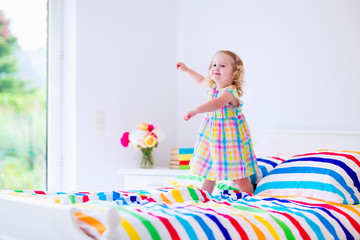 Little girl jumping on a bed