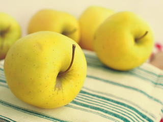Apples on wooden cutting board with green and white table napkin