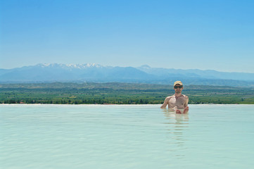 Fototapeta na wymiar young man sitting in thermal pool with mountain view