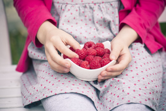 Girl with raspberries in a bowl