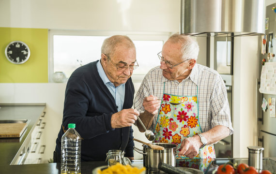 Two senior friends cooking in kitchen