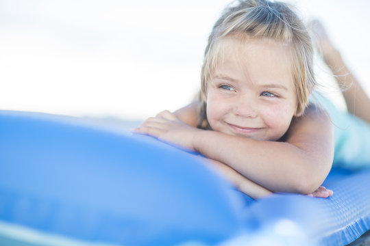 Smiling girl on beach lying on a lilo