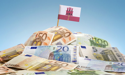 Flag of Gibraltar sticking in a pile of various european banknot