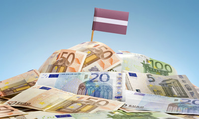 Flag of Latvia sticking in a pile of various european banknotes.