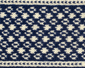 Close up on knit woolen texture. Dark blue and white dots like shapes pattern as a background.