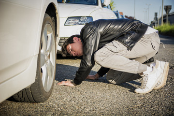 Young Man Examining Underside of Car