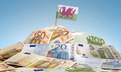 Flag of Wales sticking in a pile of various european banknotes.(