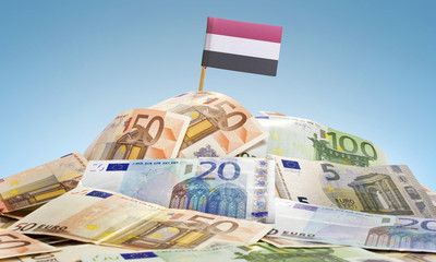 Flag of Yemen sticking in a pile of various european banknotes.(