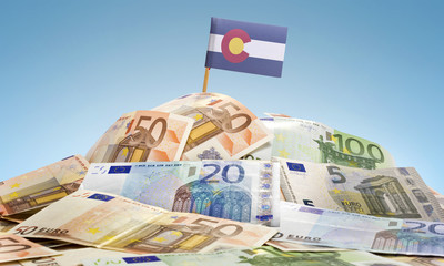 Flag of Colorado sticking in a pile of various european banknote