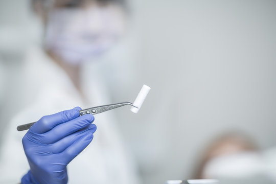 Female dentist holding tweezers and dabber