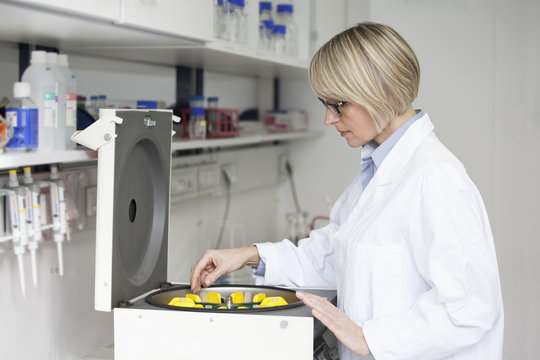 Scientist loading test tubes into small centrifuge