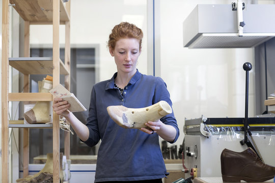 Female shoemaker looking at last
