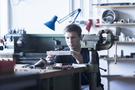 Technician at workbench constructing component part