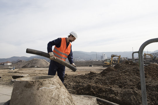 Builder holding pipe on construction site