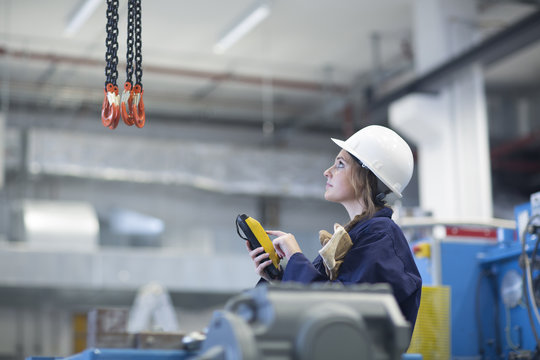 Technician in factory hall using regulator for hook